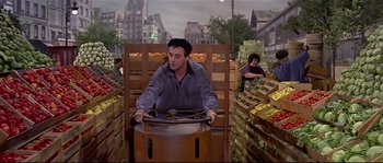 Movie still from “Irma la Douce” (1963), directed by Billy Wilder – A man riding on the back of a cart in a market; Wide shot, High angle
