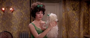 Movie still from “Irma la Douce” (1963), directed by Billy Wilder – A woman in a green dress holding a white dog; Close Up shot, Over the shoulder angle