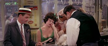 Movie still from “Irma la Douce” (1963), directed by Billy Wilder – A woman sitting at a table in front of two men; Medium shot, Over the shoulder angle