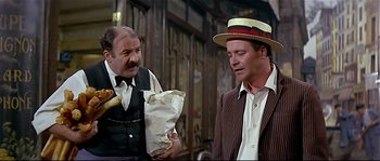 Movie still from “Irma la Douce” (1963), directed by Billy Wilder – A man wearing a straw hat is holding a paper bag and another man is wearing a suit and tie; Medium shot, Over the shoulder angle