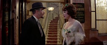 Movie still from “Irma la Douce” (1963), directed by Billy Wilder – A man and a woman standing next to each other with a dog; Medium shot, Over the shoulder angle