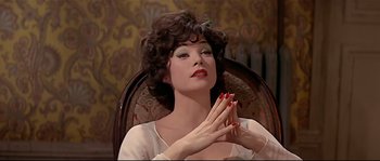 Movie still from “Irma la Douce” (1963), directed by Billy Wilder – A woman sitting in a chair clapping her hands; Close Up shot, Low angle