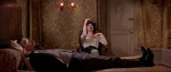 Movie still from “Irma la Douce” (1963), directed by Billy Wilder – A woman sitting on a chair in a room; Wide shot, High angle