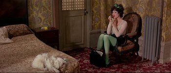 Movie still from “Irma la Douce” (1963), directed by Billy Wilder – A woman sitting on a chair in a room with a dog; Wide shot, High angle