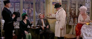 Movie still from “Irma la Douce” (1963), directed by Billy Wilder – A man in a trench coat and a hat talking to a man in a suit and tie; Medium shot, Over the shoulder angle