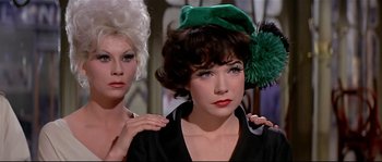 Movie still from “Irma la Douce” (1963), directed by Billy Wilder – A woman with a green hat is next to another woman with blond hair; Close Up shot, Low angle