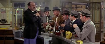 Movie still from “Irma la Douce” (1963), directed by Billy Wilder – A group of men standing around a sink in front of a counter; Wide shot, High angle