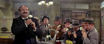Movie still from “Irma la Douce” (1963), directed by Billy Wilder – A group of men in suits and hats eating food; Medium shot, Low angle