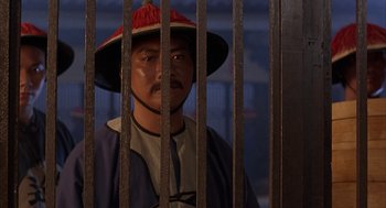 Movie still from “Iron Monkey” (1993), directed by Woo-Ping Yuen – A man wearing a hat standing behind a fence; Close Up shot, Over the shoulder angle