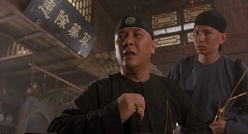 Movie still from “Iron Monkey” (1993), directed by Woo-Ping Yuen – A man in a black hat is standing in a room; Medium shot, Low angle