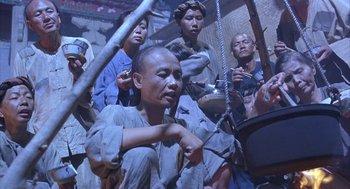 Movie still from “Iron Monkey” (1993), directed by Woo-Ping Yuen – A group of people gathered around a man with a pipe; Medium shot, High angle