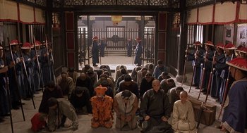 Movie still from “Iron Monkey” (1993), directed by Woo-Ping Yuen – A group of people sitting on the ground in front of a building; Wide shot, High angle
