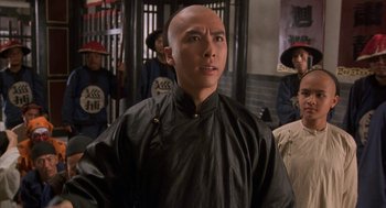 Movie still from “Iron Monkey” (1993), directed by Woo-Ping Yuen – A man with a shaved head is standing in front of a group of people; Close Up shot, Low angle