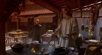 Movie still from “Iron Monkey” (1993), directed by Woo-Ping Yuen – A woman cooking food in a wok in a kitchen; Medium shot, Low angle