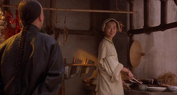 Movie still from “Iron Monkey” (1993), directed by Woo-Ping Yuen – A woman standing in front of an oven in a kitchen; Medium shot, Over the shoulder angle