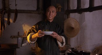 Movie still from “Iron Monkey” (1993), directed by Woo-Ping Yuen – A man holding a plate of food in his hands; Medium shot, Low angle