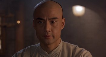 Movie still from “Iron Monkey” (1993), directed by Woo-Ping Yuen – A man with a shaved head and a white shirt; Close Up shot, Low angle
