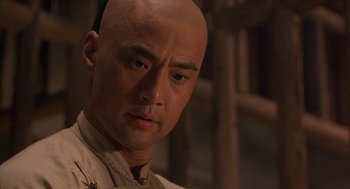 Movie still from “Iron Monkey” (1993), directed by Woo-Ping Yuen – A person with a bald head; Close Up shot, Over the shoulder angle