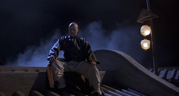 Movie still from “Iron Monkey” (1993), directed by Woo-Ping Yuen – A man sitting on top of a wooden structure; Wide shot, Low angle