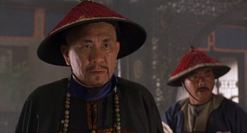 Movie still from “Iron Monkey” (1993), directed by Woo-Ping Yuen – A man wearing a red hat and a black jacket; Close Up shot, Over the shoulder angle