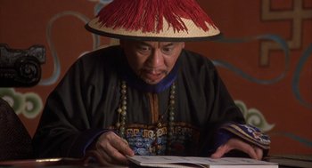Movie still from “Iron Monkey” (1993), directed by Woo-Ping Yuen – A man wearing a hat is writing on a piece of paper; Close Up shot, High angle
