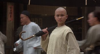 Movie still from “Iron Monkey” (1993), directed by Woo-Ping Yuen – A young man with a shaved head holding a cane; Close Up shot, Low angle