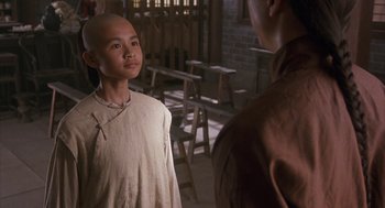 Movie still from “Iron Monkey” (1993), directed by Woo-Ping Yuen – A young man standing next to another young man in a room; Close Up shot, Over the shoulder angle