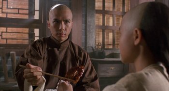 Movie still from “Iron Monkey” (1993), directed by Woo-Ping Yuen – A bald man in a brown shirt holding a wooden spoon; Close Up shot, Over the shoulder angle