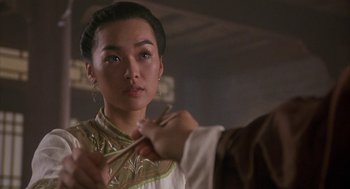 Movie still from “Iron Monkey” (1993), directed by Woo-Ping Yuen – A woman in a white and gold dress holding a pair of scissors in her hand; Close Up shot, Over the shoulder angle