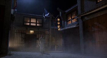 Movie still from “Iron Monkey” (1993), directed by Woo-Ping Yuen – A man standing in front of a building at night; Extreme Wide shot, Low angle
