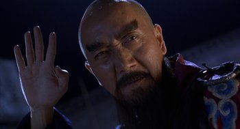 Movie still from “Iron Monkey” (1993), directed by Woo-Ping Yuen – A man with a long black beard and a mustache; Close Up shot, Low angle