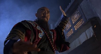 Movie still from “Iron Monkey” (1993), directed by Woo-Ping Yuen – A man with a long beard is holding his hand up; Close Up shot, Low angle