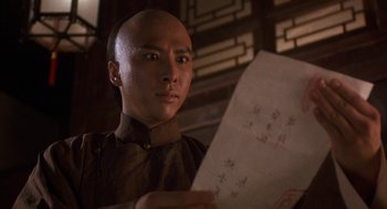 Movie still from “Iron Monkey” (1993), directed by Woo-Ping Yuen – A man holding a piece of paper while standing in a room; Close Up shot, Low angle