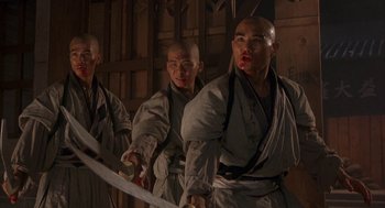 Movie still from “Iron Monkey” (1993), directed by Woo-Ping Yuen – A group of men holding a sword in front of a wall; Medium shot, Low angle
