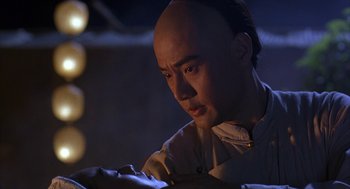 Movie still from “Iron Monkey” (1993), directed by Woo-Ping Yuen – A man with a bald head looking down at his cell phone; Close Up shot, Over the shoulder angle