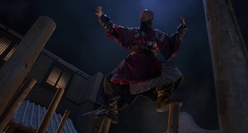 Movie still from “Iron Monkey” (1993), directed by Woo-Ping Yuen – A man in a costume jumping in the air on top of a pole; Wide shot, Low angle