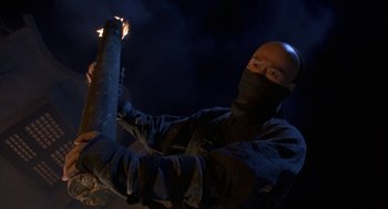 Movie still from “Iron Monkey” (1993), directed by Woo-Ping Yuen – A man holding a stick with a fire in it; Medium shot, Low angle