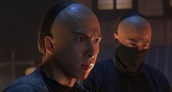 Movie still from “Iron Monkey” (1993), directed by Woo-Ping Yuen – A man with a shaved head and a bandage on his head; Close Up shot, Low angle