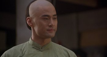 Movie still from “Iron Monkey” (1993), directed by Woo-Ping Yuen – A man with a shaved head and a green shirt; Close Up shot, Low angle