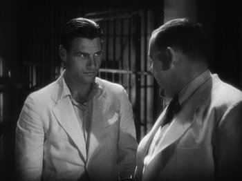 Movie still from “Island of Lost Souls” (1932), directed by Erle C. Kenton – Two men in suits talking to each other in front of a jail cell; Medium shot, Over the shoulder angle