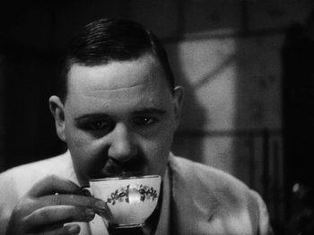 Movie still from “Island of Lost Souls” (1932), directed by Erle C. Kenton – A black and white photo of a man drinking a cup of coffee; Close Up shot, Low angle