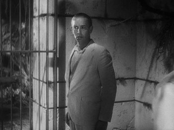 Movie still from “Island of Lost Souls” (1932), directed by Erle C. Kenton – A black and white photo of a man in a suit standing in front of a wall; Medium shot, Low angle