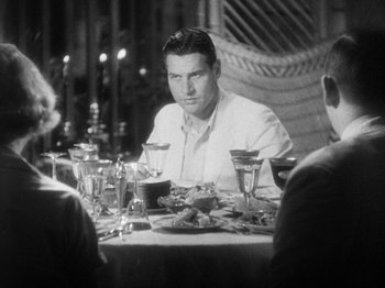 Movie still from “Island of Lost Souls” (1932), directed by Erle C. Kenton – A black and white photo of a man sitting at a dinner table; Medium shot, Over the shoulder angle
