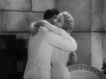 Movie still from “Island of Lost Souls” (1932), directed by Erle C. Kenton – A man and a woman hugging each other in front of a stone wall; Medium shot, High angle