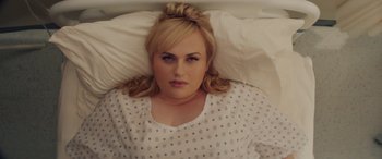 Movie still from “Isn't It Romantic” (2019), directed by Todd Strauss-Schulson – A woman laying in a bed wearing a white shirt; Close Up shot, Overhead angle
