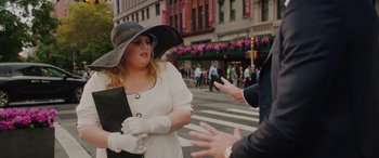 Movie still from “Isn't It Romantic” (2019), directed by Todd Strauss-Schulson – A woman wearing a hat and gloves on a city street; Medium shot, Over the shoulder angle
