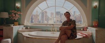 Movie still from “Isn't It Romantic” (2019), directed by Todd Strauss-Schulson – A woman sitting on a tub in front of a large window; Medium shot, Over the shoulder angle