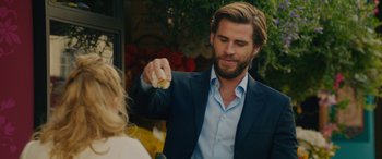 Movie still from “Isn't It Romantic” (2019), directed by Todd Strauss-Schulson – A man in a blue suit is holding a banana; Medium shot, Over the shoulder angle