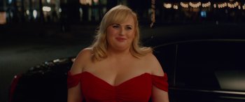 Movie still from “Isn't It Romantic” (2019), directed by Todd Strauss-Schulson – A woman in a red dress posing for a picture; Close Up shot, Over the shoulder angle