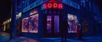 Movie still from “Isn't It Romantic” (2019), directed by Todd Strauss-Schulson – A man standing in front of a soda shop; Wide shot, Over the shoulder angle
